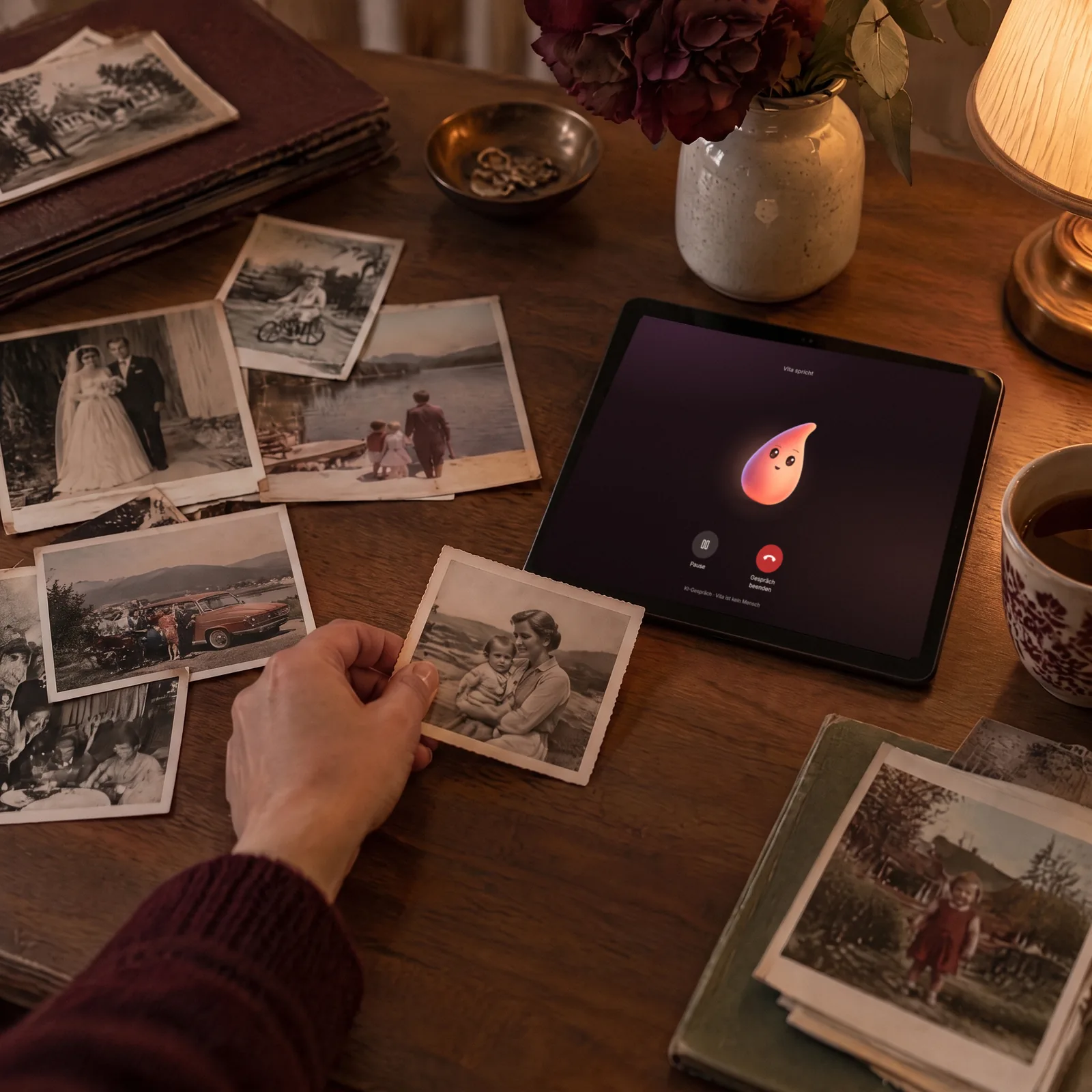 Hände legen alte Familienfotos neben ein Tablet mit Vita